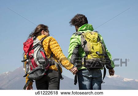 Rear view of hiking couple in front of snow capped mountain, Vogogna, Verbania, Piemonte, Italy View Large Photo Image Stock Photo - Rear view of hiking couple in front of snow capped mountain, Vogogna, Verbania, Piemonte, Italy. Fotosearch