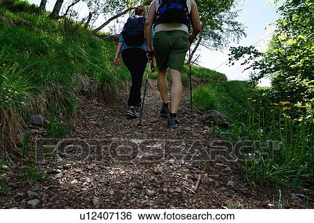 Rear view of mature male and female hikers hiking up path View Large Photo Image Stock Photograph - Rear view of mature male and female hikers hiking up path. Fotosearch