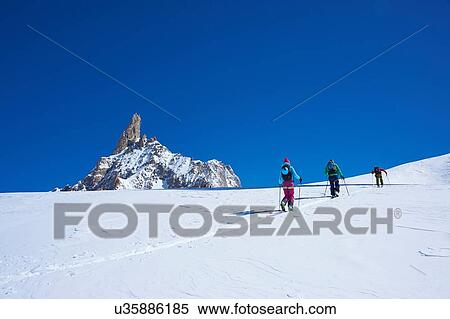 Stock Photography - Rear view of three skiers moving up Mont Blanc massif, Graian Alps, France. Fotosearch