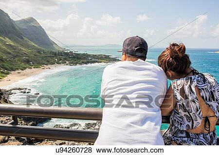 Rear view of young couple looking out from Makapuu coast, Oahu, Hawaii, USA View Large Photo Image Stock Photo - Rear view of young couple looking out from Makapuu coast, Oahu, Hawaii, USA. Fotosearch