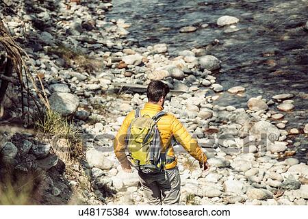Picture - Rear view of young male hiker moving down to Toce river, Vogogna, Verbania, Piemonte, Italy. Fotosearch