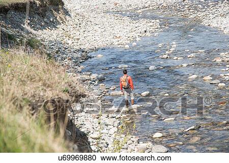 Rear view of young man hiking across Toce river, Vogogna, Verbania, Piemonte, Italy View Large Photo Image Stock Image - Rear view of young man hiking across Toce river, Vogogna, Verbania, Piemonte, Italy. Fotosearch