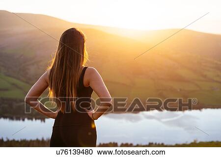 Stock Image - Rear view of young woman looking out over Talybont Reservoir in Glyn Collwn valley, Brecon Beacons, Powys, Wales. Fotosearch