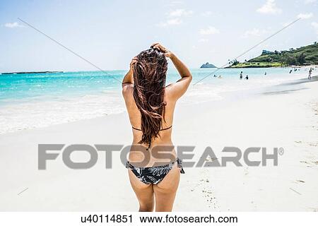 Stock Image - Rear view of young woman wearing bikini on Kailua beach, Oahu, Hawaii, USA. Fotosearch