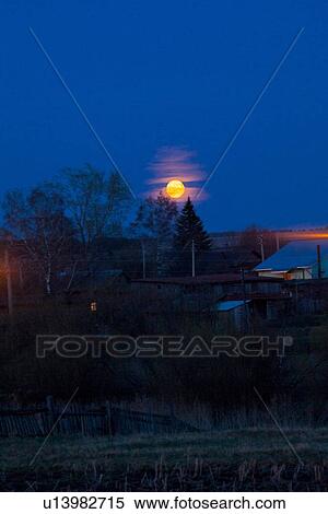 Stock Photography - Rural scene with moon shining above trees, Sarsy village, Sverdlovsk region, Russia. Fotosearch
