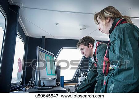Stock Photo - Scientists inspecting data on research ship. Fotosearch