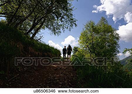 Stock Photograph - Silhouetted view of mature male and female hikers hiking up path. Fotosearch