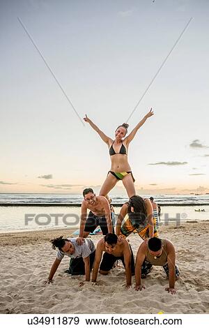 Stock Photo - Six adult friends forming human pyramid on Waikiki Beach, Hawaii, USA. Fotosearch