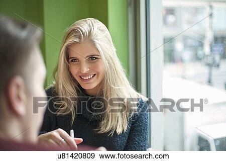 Stock Photo - Smiling young couple talking in cafe. Fotosearch