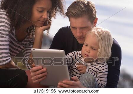 Stock Photograph - Son with parents using tablet. Fotosearch