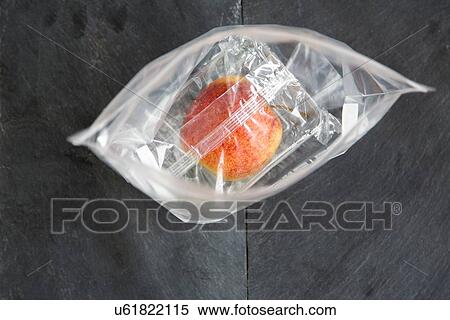 Stock Photography - Still life of apple wrapped in plastic bags. Fotosearch