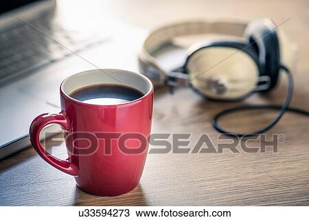 Stock Image - Still life of black coffee, headphones and laptop. Fotosearch