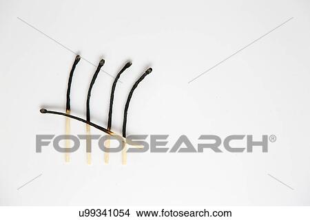 Picture - Still life with row of four burnt matches and one across. Fotosearch