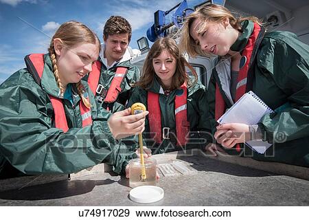 Stock Photo - Student marine biologists test sea water sample on research ship. Fotosearch