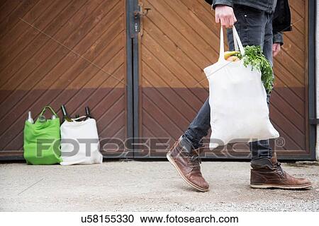 Teenage boy carrying reusable shopping bag full of fruit and veg, with bottles for recycling in yard View Large Photo Image Stock Image - Teenage boy carrying reusable shopping bag full of fruit and veg, with bottles for recycling in yard. Fotosearch