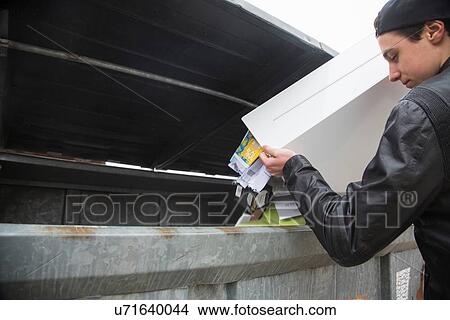 Picture - Teenage boy emptying bin with paper waste to recycling bin. Fotosearch