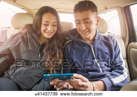 Teenage girl and young man reading smartphone text in car back seat View Large Photo Image Stock Photo - Teenage girl and young man reading smartphone text in car back seat. Fotosearch