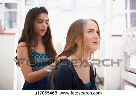 Teenage girl having hair plated by best friend in bedroom View Large Photo Image Stock Photo - Teenage girl having hair plated by best friend in bedroom. Fotosearch