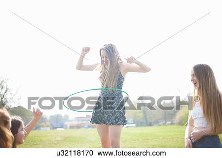 Teenage girl hoola hooping for friends in park View Large Photo Image Stock Image - Teenage girl hoola hooping for friends in park. Fotosearch