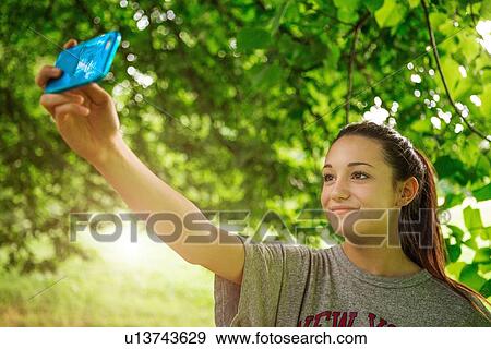 Teenage girl in park taking smartphone selfie View Large Photo Image Stock Photo - Teenage girl in park taking smartphone selfie. Fotosearch