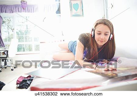 Teenage girl looking at vinyl record cover whilst listening to headphones in bedroom View Large Photo Image Stock Image - Teenage girl looking at vinyl record cover whilst listening to headphones in bedroom. Fotosearch