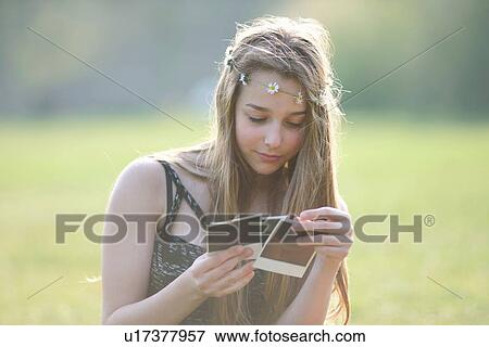 Teenage girl wearing daisy chain headdresses looking at instant photographs in park View Large Photo Image Stock Photo - Teenage girl wearing daisy chain headdresses looking at instant photographs in park. Fotosearch