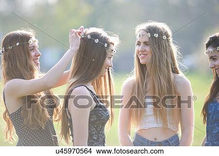 Teenage girls putting on and wearing daisy chain headdresses in park View Large Photo Image Picture - Teenage girls putting on and wearing daisy chain headdresses in park. Fotosearch