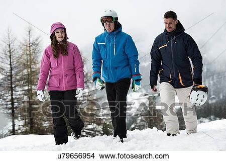 Three friends wearing skiwear walking in snow View Large Photo Image Picture - Three friends wearing skiwear walking in snow. Fotosearch