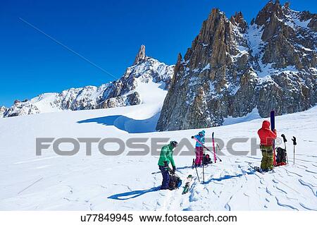 Stock Photography - Three mature skiers preparing ski equipment on Mont Blanc massif, Graian Alps, France. Fotosearch
