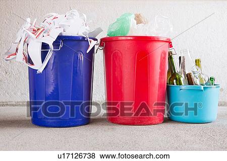 Stock Photo - Three recycling buckets in garage with paper, bottles and plastic. Fotosearch