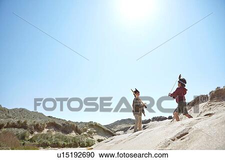 Stock Image - Two boys, wearing fancy dress, playing on sand. Fotosearch