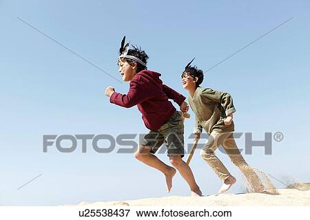 Stock Photo - Two boys, wearing fancy dress, playing on sand. Fotosearch