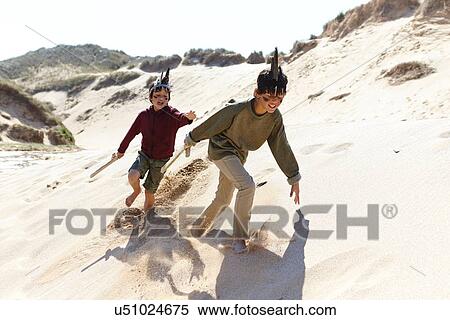 Stock Photography - Two boys, wearing fancy dress, playing on sand. Fotosearch