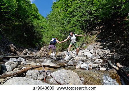 Stock Photo - Two mature hikers crossing river. Fotosearch