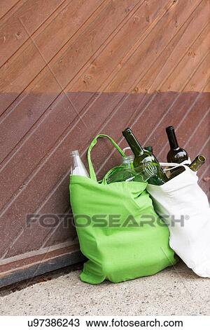 Stock Image - Two reusable shopping bags full of bottles for recycling in yard. Fotosearch