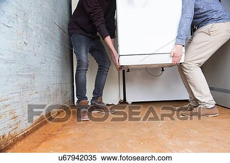 Stock Photography - Two teenage boys recycling white goods in recycling depot. Fotosearch