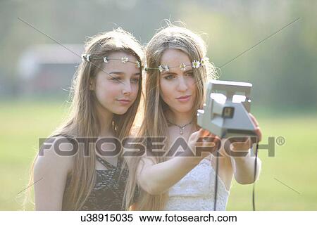 Two teenage girls in park taking instant camera selfie View Large Photo Image Stock Photography - Two teenage girls in park taking instant camera selfie. Fotosearch