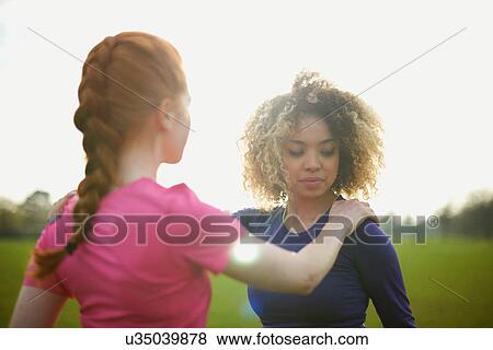 Stock Photo - Two women exercising and stretching in the park. Fotosearch