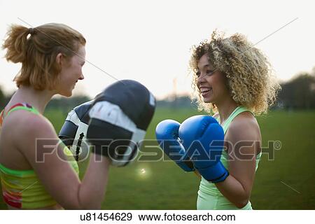 Stock Photo - Two women exercising with boxing gloves in the park. Fotosearch