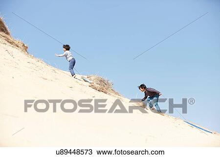 Two young boys climbing sandy hill, pulling sledges behind them View Large Photo Image Stock Image - Two young boys climbing sandy hill, pulling sledges behind them. Fotosearch