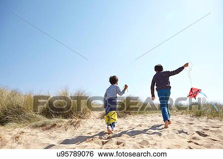 Stock Photograph - Two young boys, flying kites on beach. Fotosearch