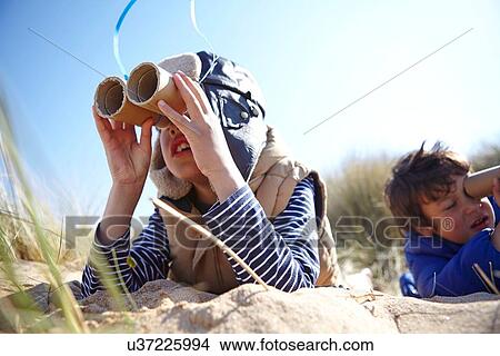 Two young boys on beach, looking through pretend binoculars View Large Photo Image Picture - Two young boys on beach, looking through pretend binoculars. Fotosearch