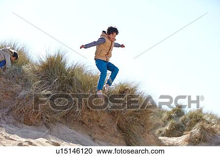 Two young boys playing on beach and sand dunes View Large Photo Image Stock Image - Two young boys playing on beach and sand dunes. Fotosearch