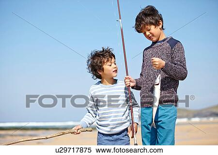 Two young boys standing together, holding fishing rod and fish View Large Photo Image Stock Photography - Two young boys standing together, holding fishing rod and fish. Fotosearch