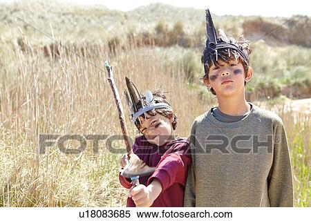 Stock Photography - Two young boys wearing fancy dress, holding home-made bow and arrow. Fotosearch