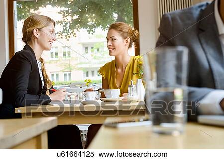 Two young female friends chatting in cafe View Large Photo Image Stock Photography - Two young female friends chatting in cafe. Fotosearch