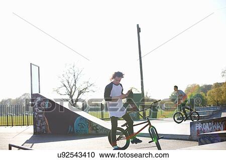 Stock Image - Two young men on bmx bikes at skatepark. Fotosearch