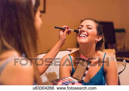Two young women, applying make-up View Large Photo Image Stock Photograph - Two young women, applying make-up. Fotosearch