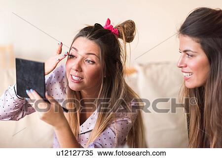 Two young women, applying make-up View Large Photo Image Stock Photography - Two young women, applying make-up. Fotosearch