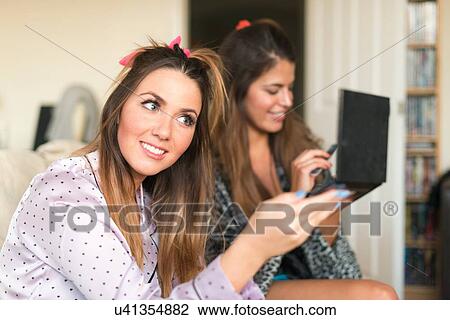 Two young women at home, doing hair and make-up View Large Photo Image Stock Image - Two young women at home, doing hair and make-up. Fotosearch